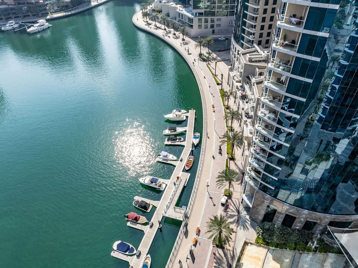 A marina seen from the water, yachts moored below the towers.
